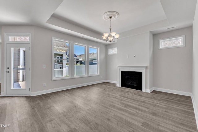 1217 Linkwood Way, Fuquay Varina, NC 27526 - unfurnished living room with a tray ceiling, a chandelier, wood finished floors, and healthy amount of natural light