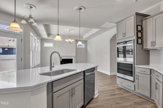 1217 Linkwood Way, Fuquay Varina, NC 27526 - kitchen featuring gray cabinets, a sink, appliances with stainless steel finishes, and a tray ceiling