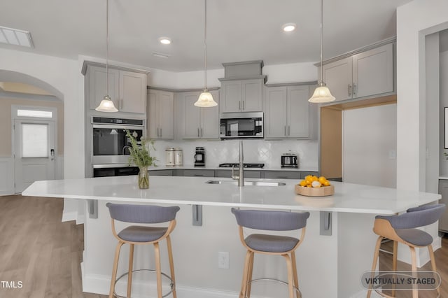 1217 Linkwood Way, Fuquay Varina, NC 27526 - kitchen featuring gray cabinetry, stainless steel microwave, arched walkways, double oven, and recessed lighting