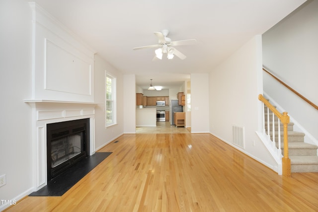 803 High Ct, Hillsborough, NC 27278 - unfurnished living room featuring light wood-type flooring, ceiling fan, stairs, a glass covered fireplace, and baseboards
