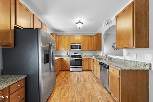1154 Bungalow Park Dr, Apex, NC 27502 - kitchen with appliances with stainless steel finishes, a sink, light wood finished floors, arched walkways, and brown cabinets