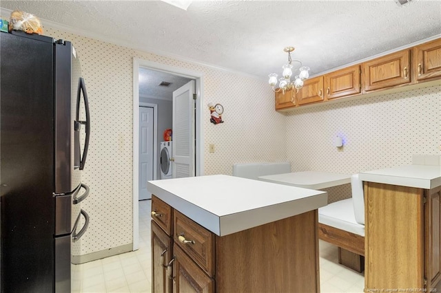 21621 Old Maxton Rd, Maxton, NC 28364 - kitchen with freestanding refrigerator, light floors, washer / dryer, a textured ceiling, and ornamental molding