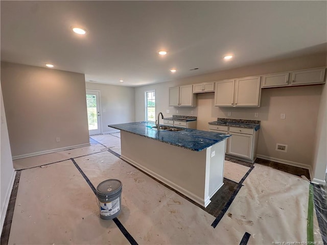 112 Dalton Dr, Lumber Bridge, NC 28357 - kitchen with a sink, baseboards, an island with sink, recessed lighting, and dark stone counters