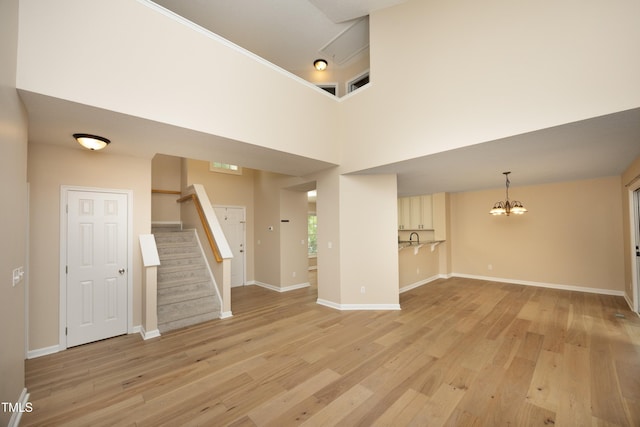 105 Old Dock Trl, Cary, NC 27519 - unfurnished living room with a chandelier, light wood-style flooring, stairway, and baseboards