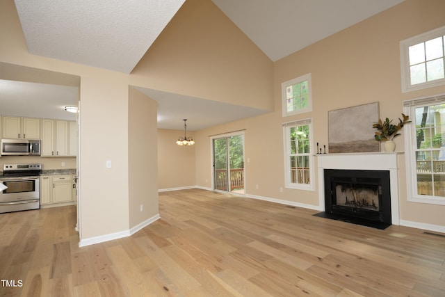 105 Old Dock Trl, Cary, NC 27519 - unfurnished living room featuring a fireplace with flush hearth, light wood-style flooring, a chandelier, high vaulted ceiling, and baseboards