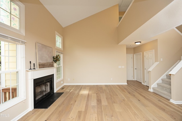 105 Old Dock Trl, Cary, NC 27519 - unfurnished living room featuring high vaulted ceiling, wood finished floors, a fireplace with flush hearth, baseboards, and stairs