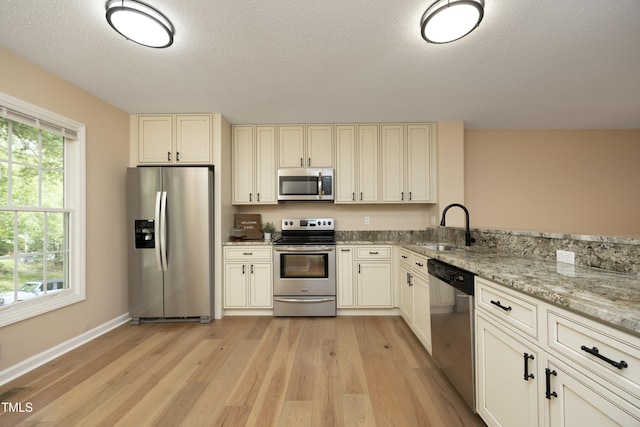 105 Old Dock Trl, Cary, NC 27519 - kitchen featuring stainless steel appliances, a sink, light wood-type flooring, light stone counters, and a textured ceiling