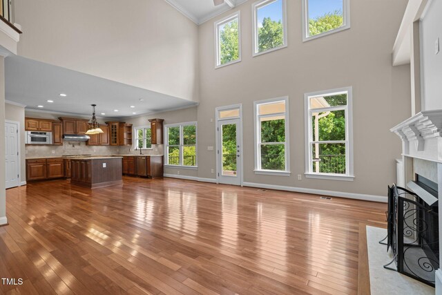 7409 Chesley Ln, Durham, NC 27713 - unfurnished living room featuring crown molding, plenty of natural light, a fireplace with flush hearth, baseboards, and a towering ceiling