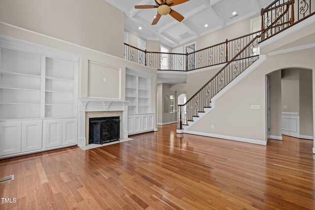 7409 Chesley Ln, Durham, NC 27713 - unfurnished living room with arched walkways, ceiling fan, plenty of natural light, coffered ceiling, and a high ceiling