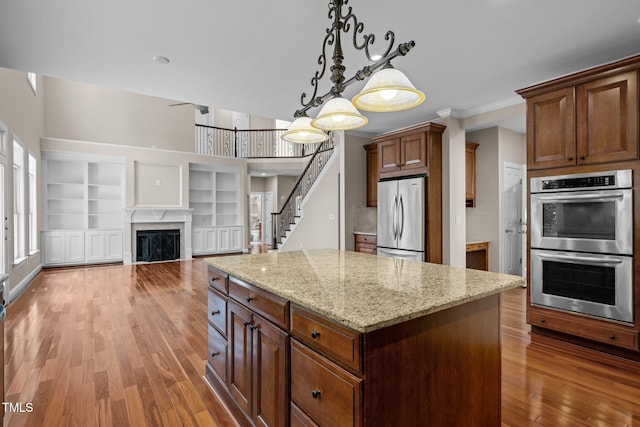 7409 Chesley Ln, Durham, NC 27713 - kitchen with stainless steel appliances, light wood finished floors, a center island, hanging light fixtures, and light stone countertops