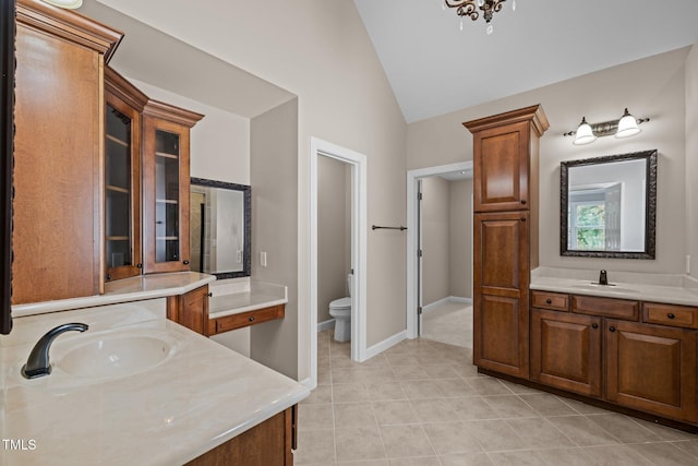7409 Chesley Ln, Durham, NC 27713 - full bath with vaulted ceiling, two vanities, toilet, tile patterned floors, and baseboards
