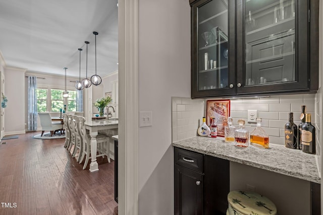 12216 Kyle Abbey Ln, Raleigh, NC 27613 - indoor dry bar featuring dark wood-style floors, backsplash, pendant lighting, ornamental molding, and baseboards