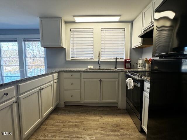 509 Cedar Creek Rd, Fayetteville, NC 28312 - kitchen with freestanding refrigerator, electric range oven, under cabinet range hood, wood finished floors, and dark stone countertops