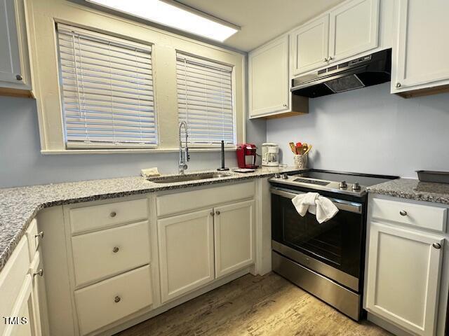 509 Cedar Creek Rd, Fayetteville, NC 28312 - kitchen with stainless steel electric range, under cabinet range hood, light wood-style flooring, and white cabinets