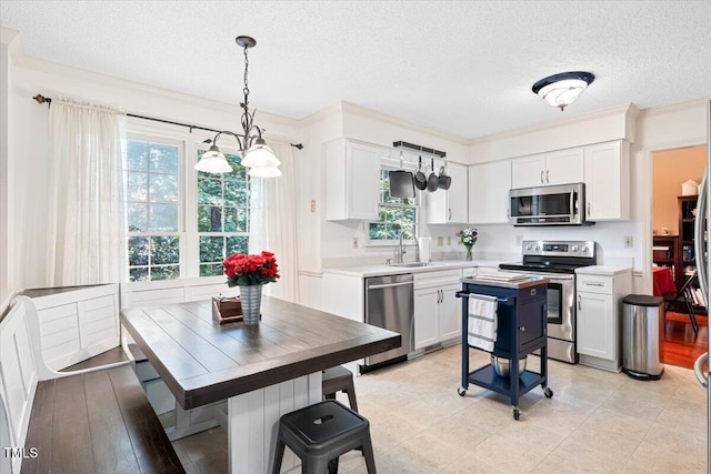 107 Canyon Run, Cary, NC 27513 - kitchen featuring appliances with stainless steel finishes, a textured ceiling, a sink, light countertops, and white cabinets