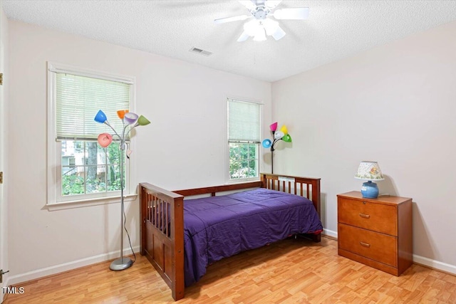 107 Canyon Run, Cary, NC 27513 - bedroom with light wood-style floors, multiple windows, a textured ceiling, baseboards, and a ceiling fan