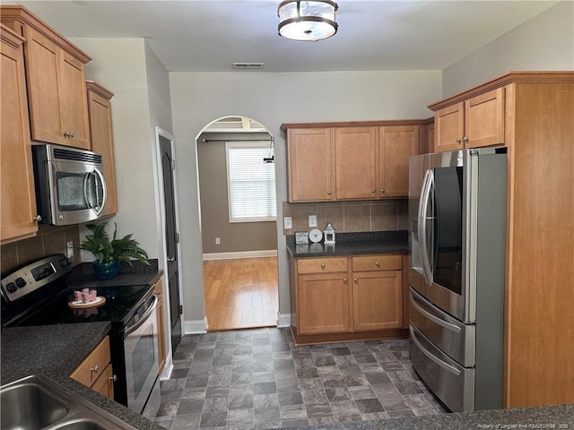 1545 Gallant Fox Ct, Parkton, NC 28371 - kitchen with appliances with stainless steel finishes, arched walkways, backsplash, baseboards, and a sink