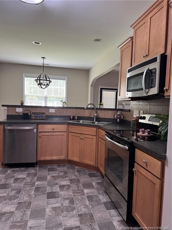 1545 Gallant Fox Ct, Parkton, NC 28371 - kitchen with stainless steel appliances, a sink, dark countertops, brown cabinetry, and recessed lighting