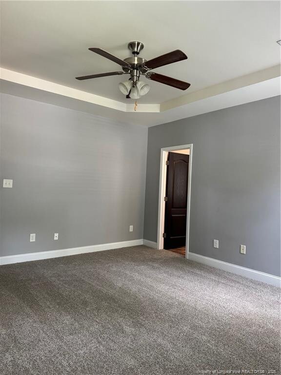 1545 Gallant Fox Ct, Parkton, NC 28371 - unfurnished room with a raised ceiling, a ceiling fan, dark carpet, and baseboards