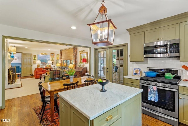 3308 Cobblestone Ct, Raleigh, NC 27607 - kitchen featuring stainless steel appliances, green cabinetry, french doors, decorative backsplash, and light wood-style flooring