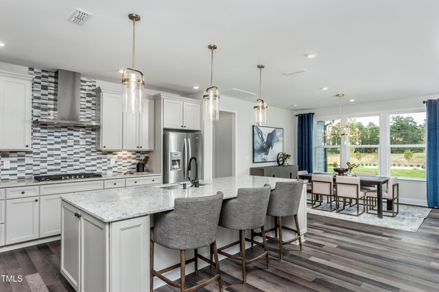 2516 Del Webb Gardens Dr, Fuquay Varina, NC 27526 - kitchen with stainless steel fridge with ice dispenser, dark wood finished floors, wall chimney exhaust hood, a sink, and black cooktop