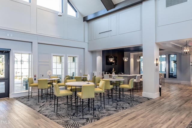 2516 Del Webb Gardens Dr, Fuquay Varina, NC 27526 - dining space featuring a towering ceiling, wood finished floors, healthy amount of natural light, and beam ceiling