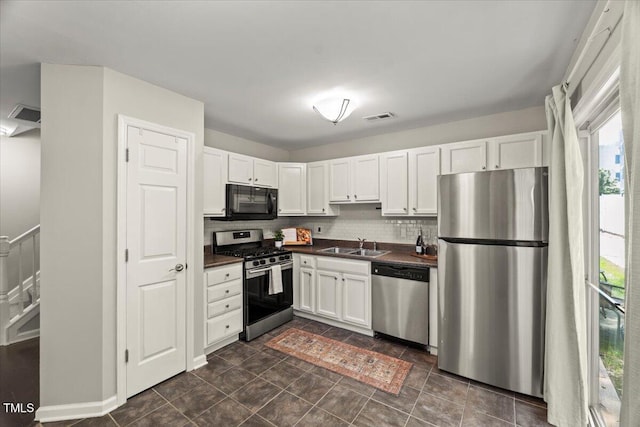 2920 Barrymore St Unit 106, Raleigh, NC 27603 - kitchen with stainless steel appliances, dark countertops, white cabinetry, and tasteful backsplash