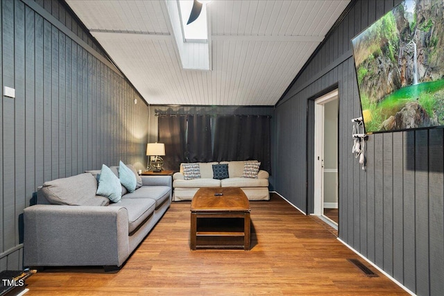 9801 Honeycutt Rd, Raleigh, NC 27614 - living room with vaulted ceiling, a skylight, wood finished floors, and wooden walls