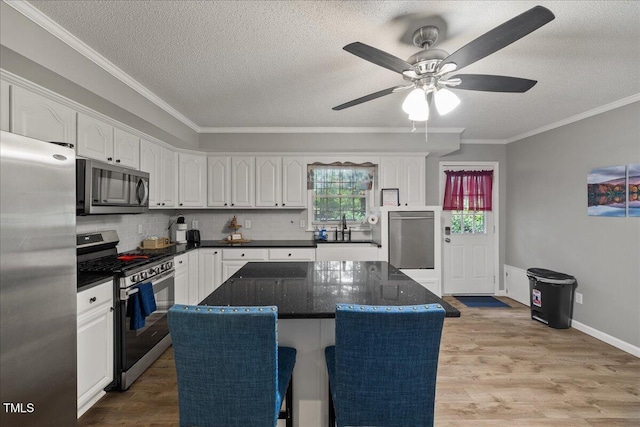 9801 Honeycutt Rd, Raleigh, NC 27614 - kitchen with stainless steel appliances, a sink, a textured ceiling, ornamental molding, and white cabinets