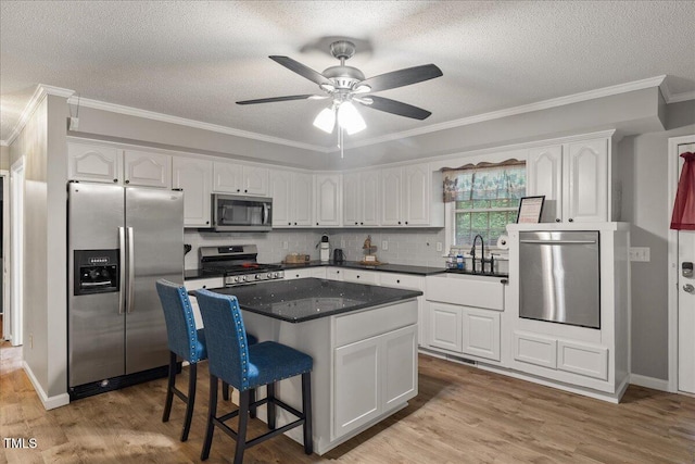 9801 Honeycutt Rd, Raleigh, NC 27614 - kitchen with stainless steel appliances, white cabinetry, wood finished floors, a kitchen island, and a textured ceiling