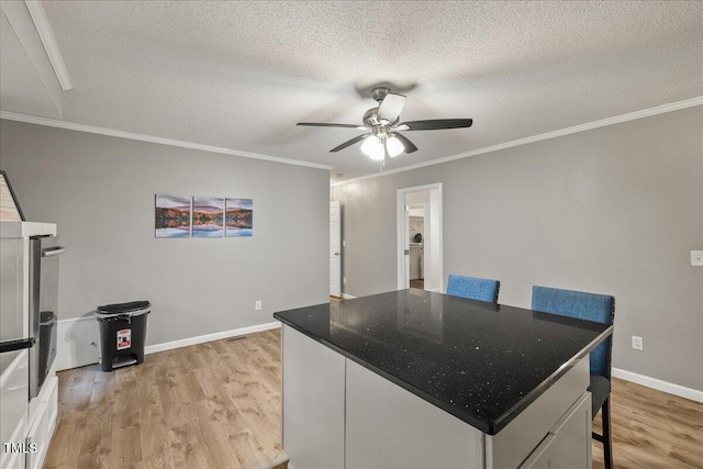 9801 Honeycutt Rd, Raleigh, NC 27614 - kitchen featuring light wood-type flooring, a ceiling fan, a textured ceiling, a center island, and ornamental molding
