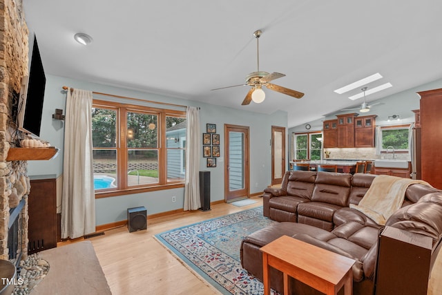 502 Hillcrest Rd, Apex, NC 27502 - living room featuring ceiling fan, a skylight, lofted ceiling, light wood-style flooring, and a fireplace