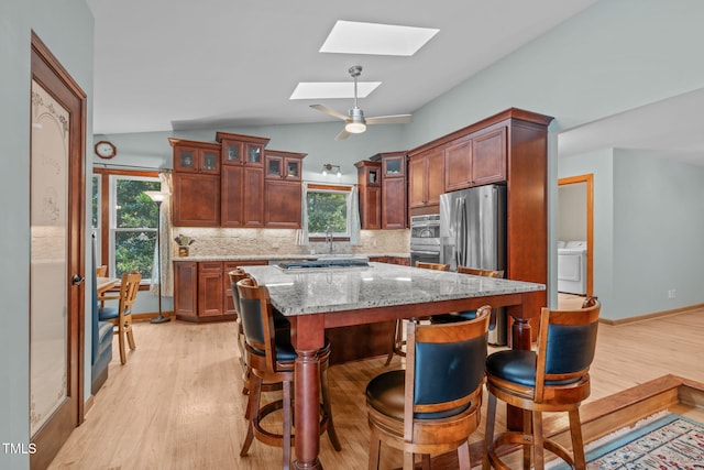 502 Hillcrest Rd, Apex, NC 27502 - kitchen featuring washer / dryer, a skylight, appliances with stainless steel finishes, light wood-style flooring, and vaulted ceiling