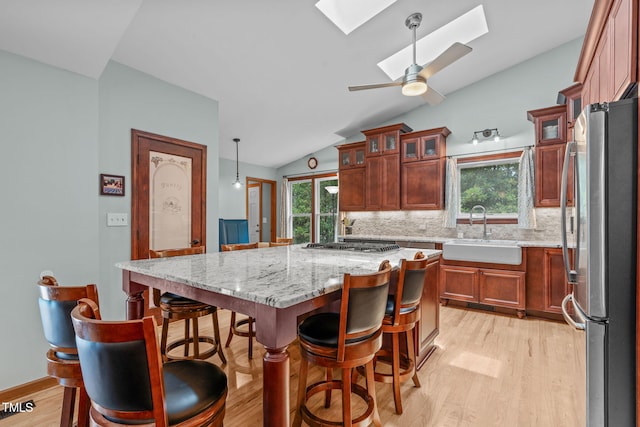 502 Hillcrest Rd, Apex, NC 27502 - kitchen featuring freestanding refrigerator, light wood-style floors, a skylight, vaulted ceiling, and decorative backsplash