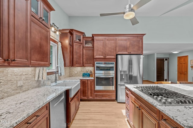 502 Hillcrest Rd, Apex, NC 27502 - kitchen featuring appliances with stainless steel finishes, light stone countertops, light wood-style floors, backsplash, and a ceiling fan