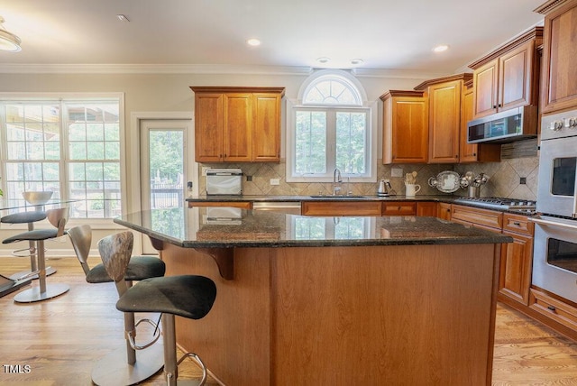 1005 Hidden River Ct, Raleigh, NC 27614 - kitchen featuring stainless steel appliances, a center island, crown molding, a sink, and a kitchen bar