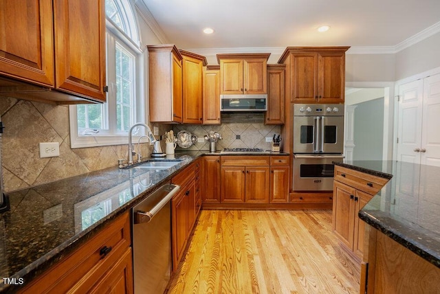 1005 Hidden River Ct, Raleigh, NC 27614 - kitchen with a sink, appliances with stainless steel finishes, brown cabinets, crown molding, and light wood-style floors