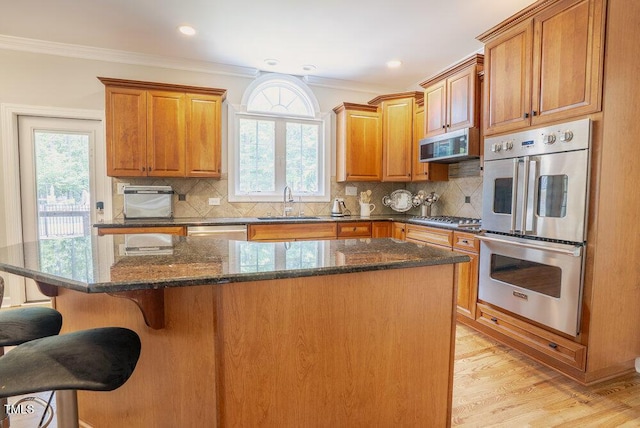 1005 Hidden River Ct, Raleigh, NC 27614 - kitchen featuring stainless steel appliances, a sink, light wood-style floors, a breakfast bar area, and ornamental molding