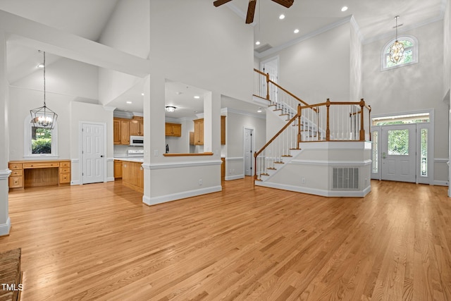 5108 Briton Pl, Fuquay Varina, NC 27526 - unfurnished living room with a towering ceiling, healthy amount of natural light, stairway, light wood finished floors, and a chandelier