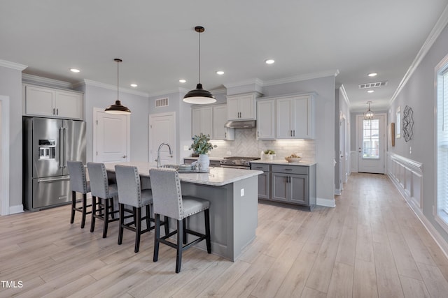 3020 High Plains Dr, Fuquay Varina, NC 27526 - kitchen with high quality appliances, under cabinet range hood, light wood-type flooring, backsplash, and an island with sink