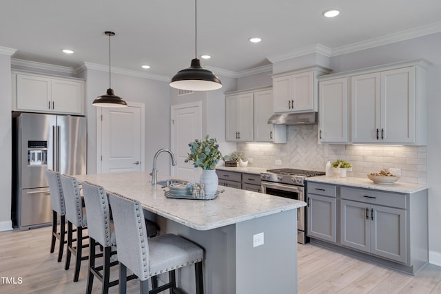3020 High Plains Dr, Fuquay Varina, NC 27526 - kitchen featuring appliances with stainless steel finishes, a sink, under cabinet range hood, light stone counters, and a kitchen island with sink