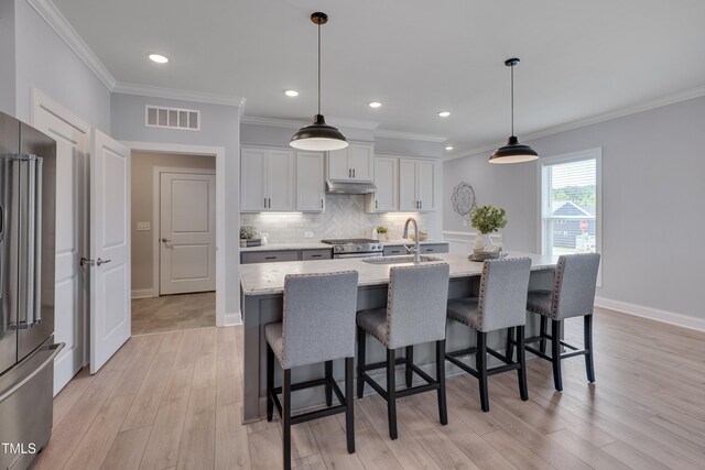 3020 High Plains Dr, Fuquay Varina, NC 27526 - kitchen featuring stainless steel appliances, a sink, light wood-style flooring, backsplash, and a breakfast bar area