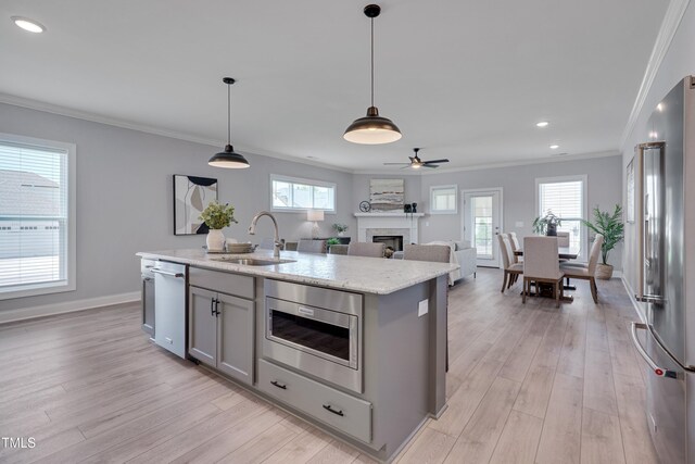 3020 High Plains Dr, Fuquay Varina, NC 27526 - kitchen with appliances with stainless steel finishes, a sink, gray cabinets, a fireplace, and light wood-style flooring