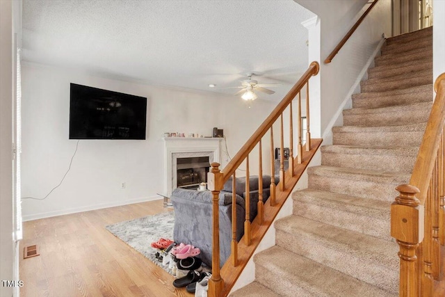 4108 Lazyriver Ln, Durham, NC 27712 - staircase with ceiling fan, wood finished floors, a textured ceiling, a premium fireplace, and baseboards