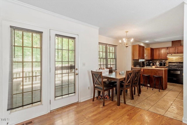 4108 Lazyriver Ln, Durham, NC 27712 - dining space with a chandelier, light wood-type flooring, crown molding, and a textured ceiling