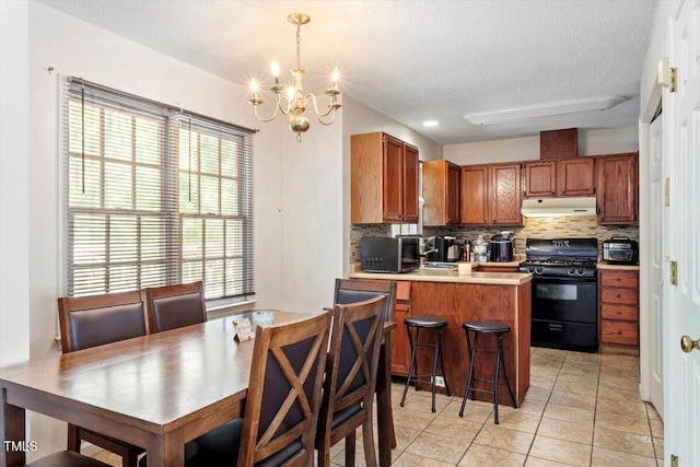 4108 Lazyriver Ln, Durham, NC 27712 - kitchen with gas stove, under cabinet range hood, a textured ceiling, stainless steel microwave, and backsplash