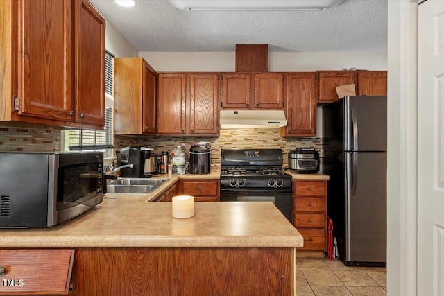 4108 Lazyriver Ln, Durham, NC 27712 - kitchen featuring stainless steel appliances, under cabinet range hood, a sink, brown cabinetry, and a textured ceiling