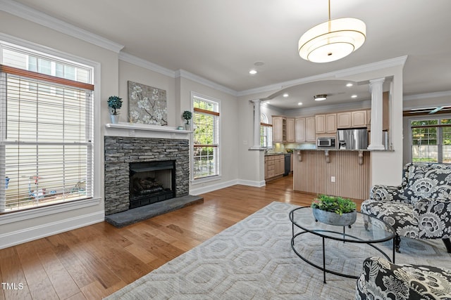 4913 Great Meadows Ct, Raleigh, NC 27609 - living room with crown molding, baseboards, light wood-type flooring, ornate columns, and a stone fireplace