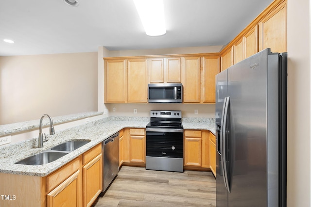5644 Picnic Rock Ln, Raleigh, NC 27613 - kitchen featuring appliances with stainless steel finishes, light brown cabinetry, light wood-type flooring, light stone counters, and a peninsula