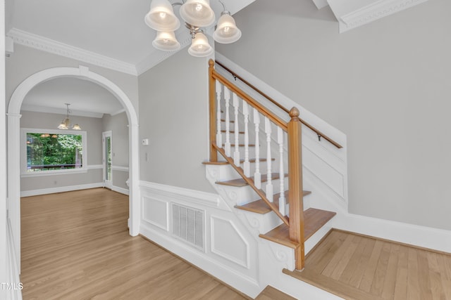 6201 Bayswater Trl, Raleigh, NC 27612 - stairs featuring a chandelier, wood finished floors, crown molding, and arched walkways